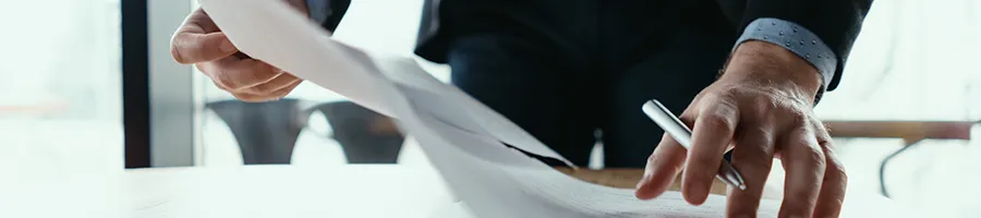 A man holding a pen while doing paperwork in an LLC office