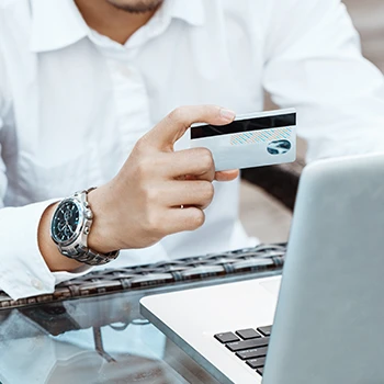 A business man holding a credit card while working on a laptop