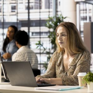 Confident businesswoman working at a desk in corporation, reviewing financial reports on her laptop. Successful employee managing business tasks and developing a strategy plan for the company.