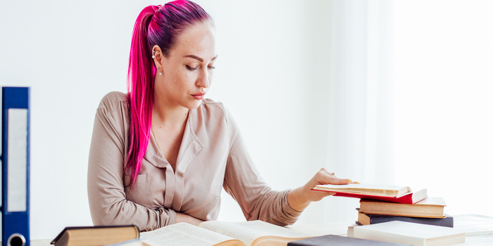 business woman with pink hair sits in the Office reads books education